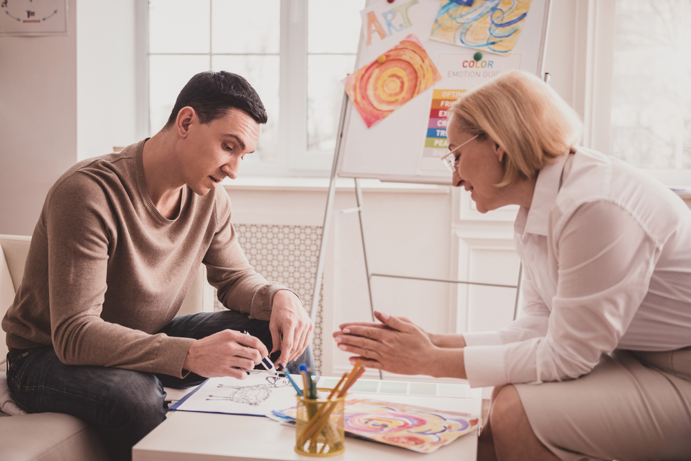 a man drawing and a woman watches him