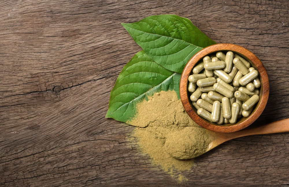photo of kratom leaves, powder, and bowl with kratom capsules. Users of kratom may wonder "How long does it take to withdraw from kratom?"