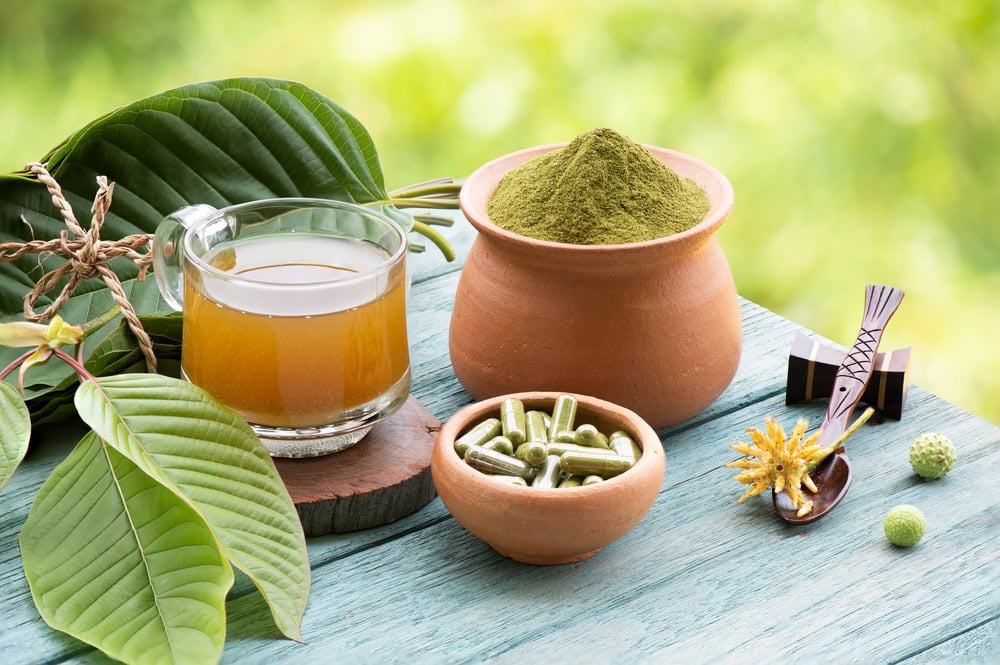 photo of crushed kratom in a bowl, kratom tea in a mug, and a bowl with kratom capsules.